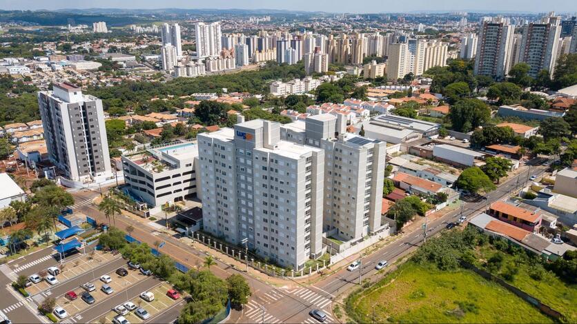 Imagem aérea da fachada do condomínio Luggo Mansões em Campinas. É possível ver o prédio e seus arredores: ruas, outras edificações, um lago e uma região arborizada.