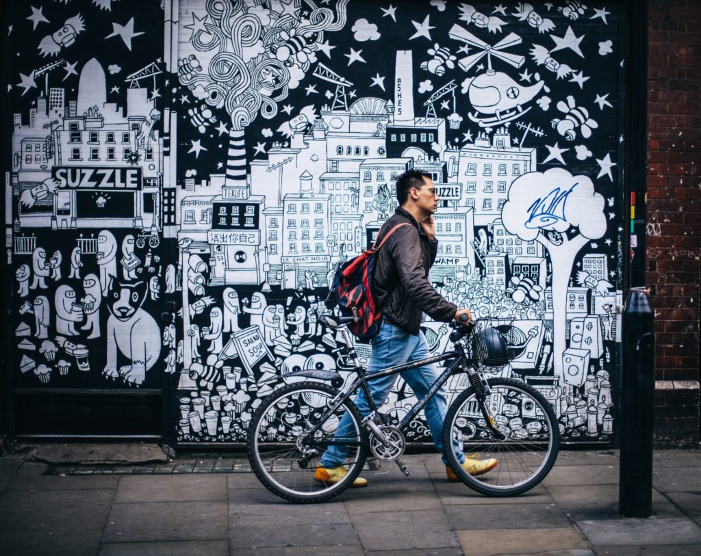 Homem levando bicicleta pela rua
