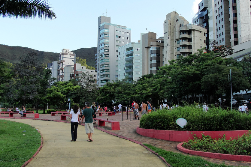 A imagem mostra um casal caminhando em um parque de belo horizonte.