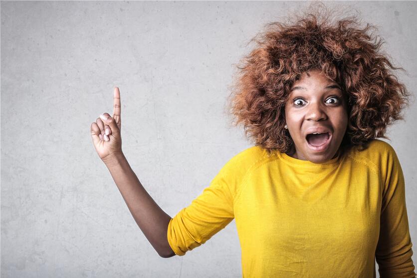 A imagem mostra uma mulher com cabelos arrepiados apontando para o teto com cara de surpresa pelo barulho que os vizinhos estão fazendo