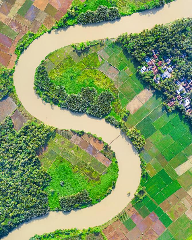 A imagem mostra uma imagem aérea de um terreno grande dividido em vários terrenos menores margeando um rio, para ilustrar um condomínio de lotes