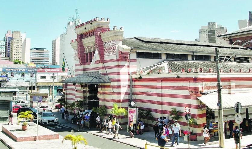 Fachada do Mercado Municipal de Campinas, durante um dia ensolarado. Há pequena movimentação na rua.