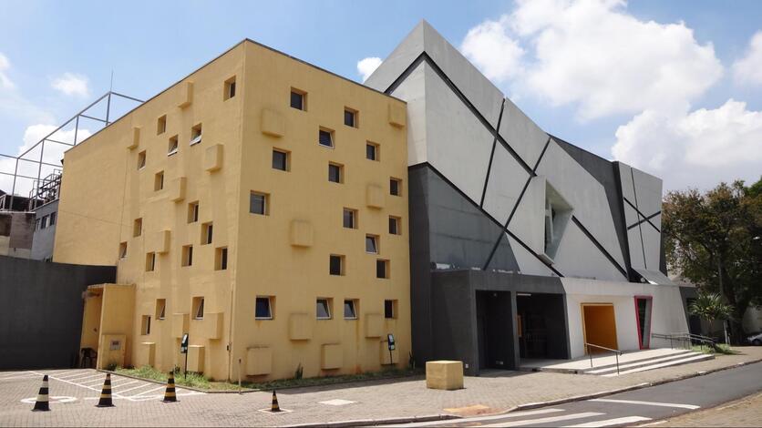 Fachada do Teatro Municipal Castro Mendes à luz do dia. À esquerda, o prédio é retangular e amarelo, e à direita possui uma fachada de vidro na diagonal.