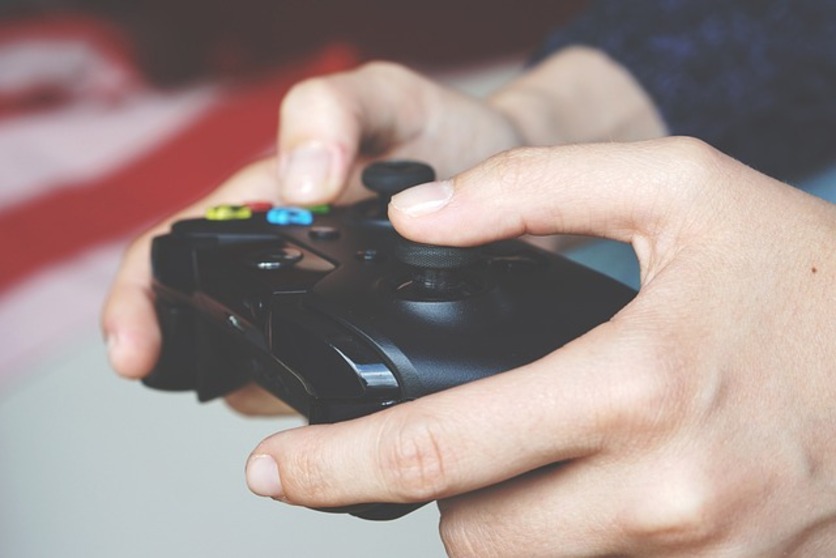 A imagem mostra duas mãos segurando um controle de video game para ilustrar o que não fazer nas pausas no trabalho