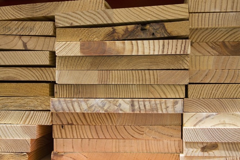 A imagem mostra várias placas de madeira formando uma pilha e com um zoom no material para ilustrar a importância de verificar o material da divisória.