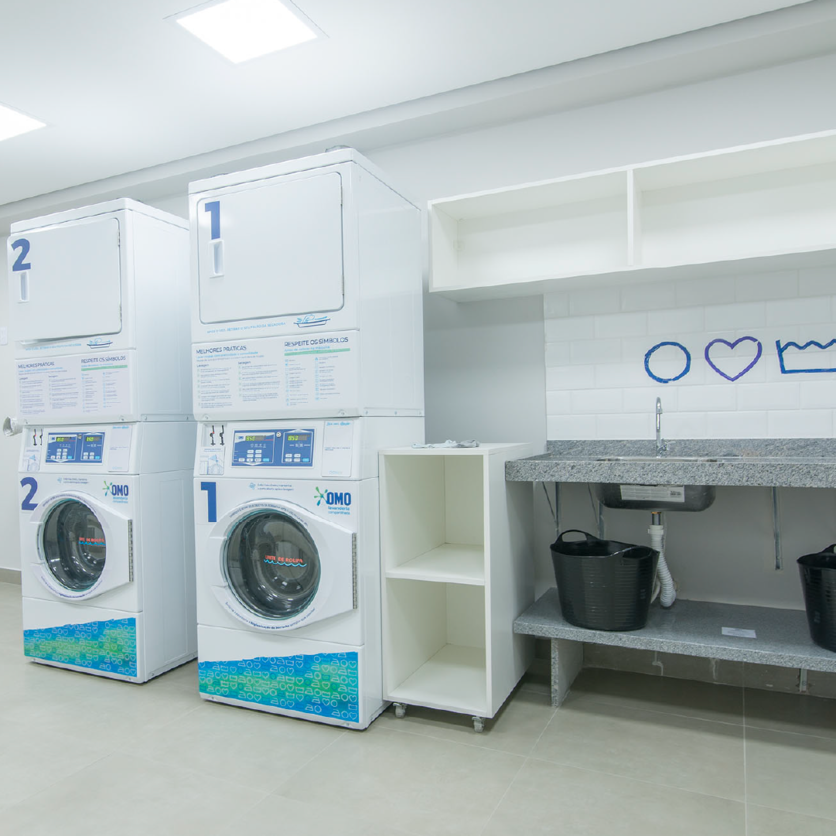 A imagem mostra uma lavanderia com máquinas de lavar e secar novinhas para ilustrar a lavanderia compartilhada do Luggo Parque Industrial