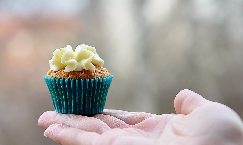 A imagem mostra uma mão estendida com um cupcake  sobre a palma para ilustrar os pequenos produtores que mantém o mercado imobiliário 2023 aquecido 