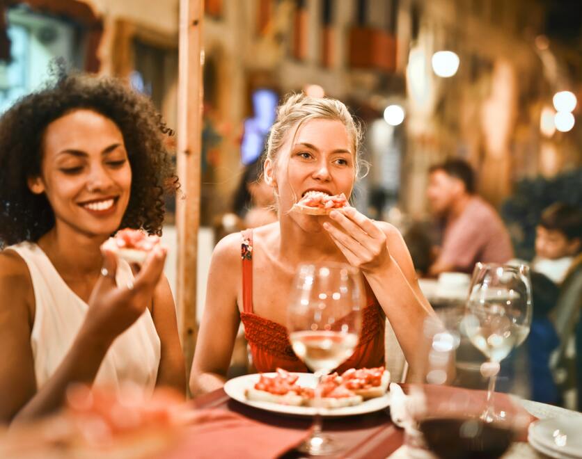 A imagem mostra duas mulheres jantando em um restaurante para ilustrar as opções de lazer em Porto Alegre, para quem deseja morar no Jardim Carvalho.