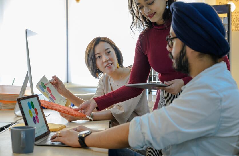 três pessoas conversando em uma mesa e pensando na alocação de colaboradores no aluguel para empresas