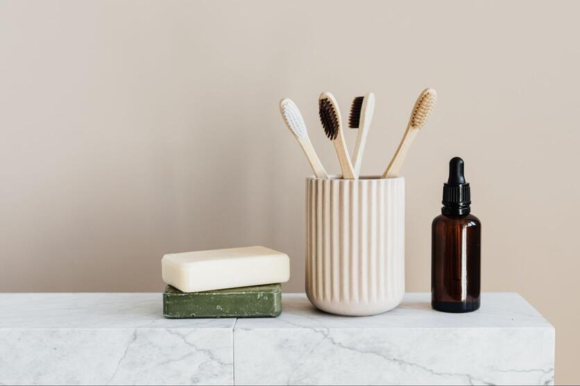 imagem de 2 sabonetes em barra, escovas de dente de madeira e um vidro de óleo essencial para consumo sustentável