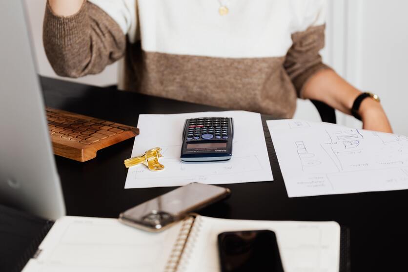 pessoa em frente a mesa com caderno, calculadora e outros itens de escritório para ilustrar o IPTU