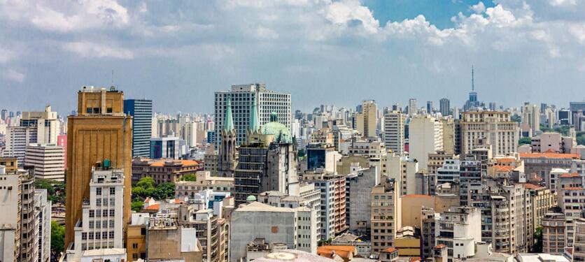 Prédios ao centro de São Paulo vistos de cima, com as torres de uma catedral ao meio.