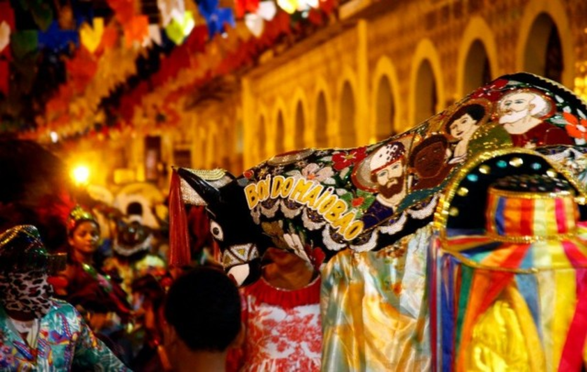 Festa Boi-Bumbá no Amazonas, com pessoas fantasiadas na rua e uma bandeira temática.