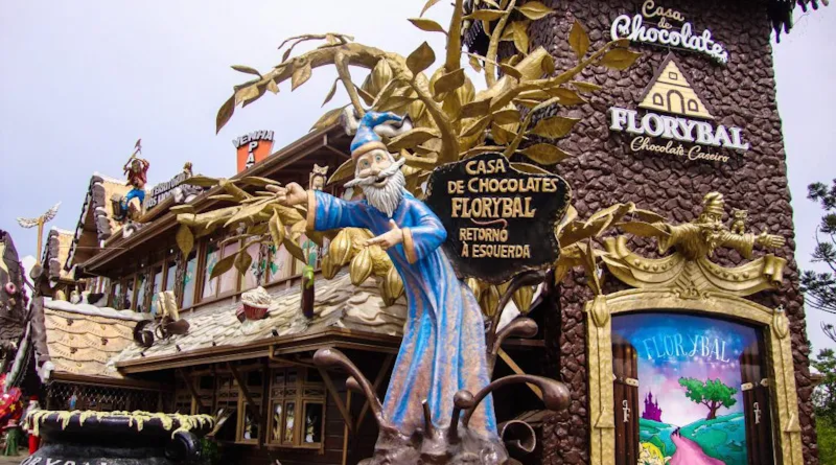Fachada da Casa de Chocolates Florybal, com a estátua de um mago em frente à estrutura decorada.