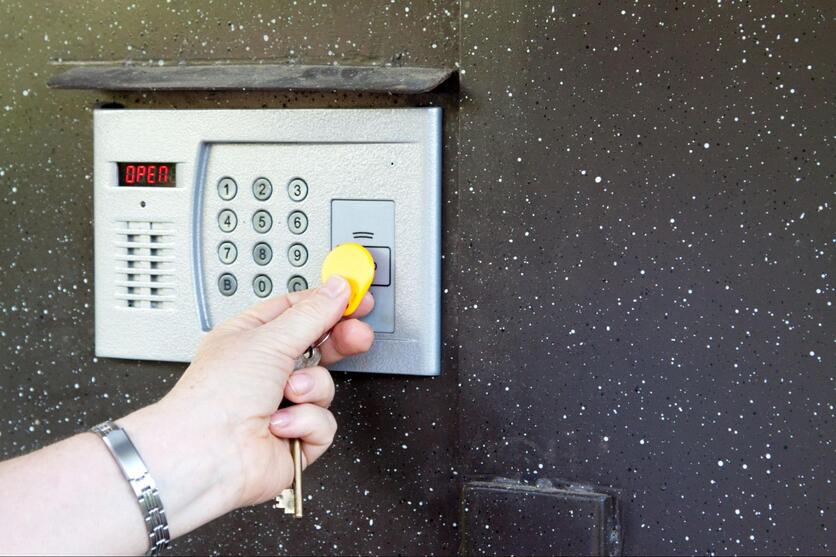 Mão aproximando uma tag em frente ao leitor de acesso de segurança em um condomínio inteligente.
