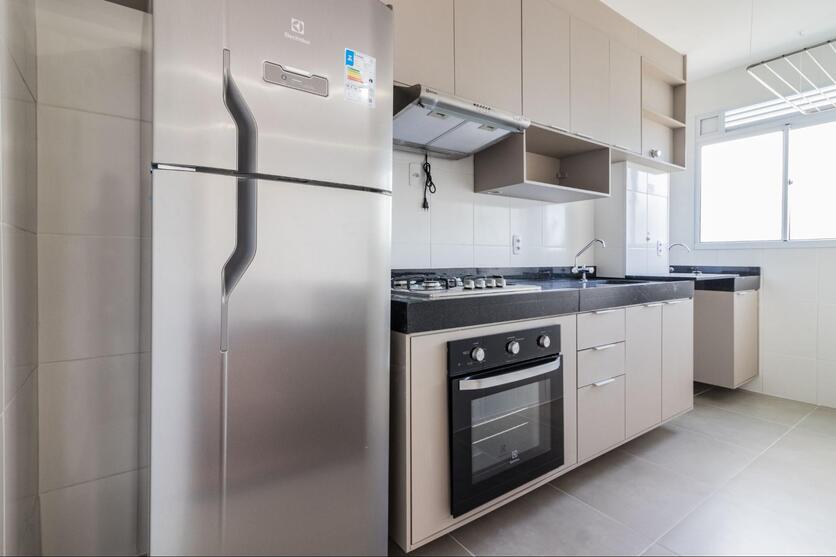 Cozinha de apartamento Luggo, com balcões de cozinha, armários, fogão, pia e geladeira. 