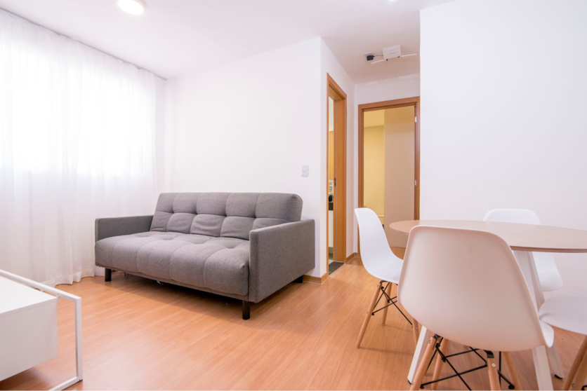 Sala de estar de apartamento Luggo, mobiliada com sofá, mesa e cadeiras e rack.