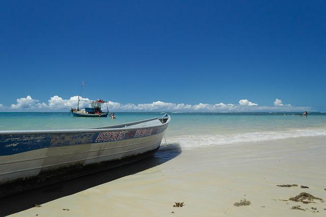 Litoral de praia, com dois barcos pequenos à vista.