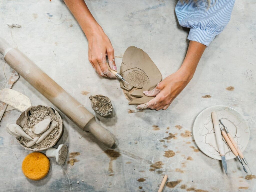 Duas mãos fazendo artesanato com cerâmica.