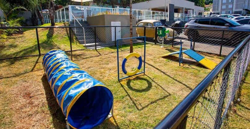 Visão de um espaço pet dos condomínios Luggo. Espaço gramado e cercado, com túnel, arcos e rampa.