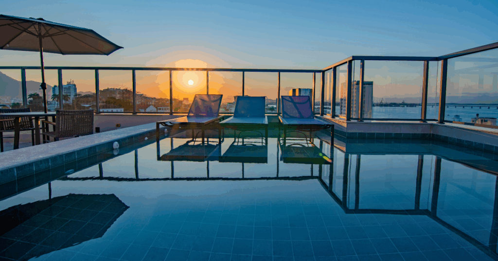 Ampla área da piscina do condomínio Luggo Mauá, com deck e espreguiçadeiras, destacando o espaço de lazer e bem-estar para os moradores.